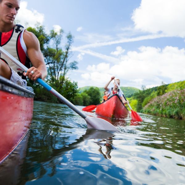 Group kayaking in red kayaks with oars